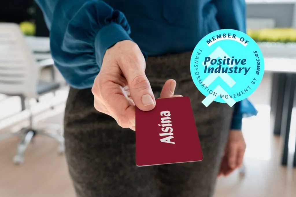 Una persona que sujeta una tarjeta NFC en su mano. La tarjeta es de color rojo granate, con el logo de Alsina.